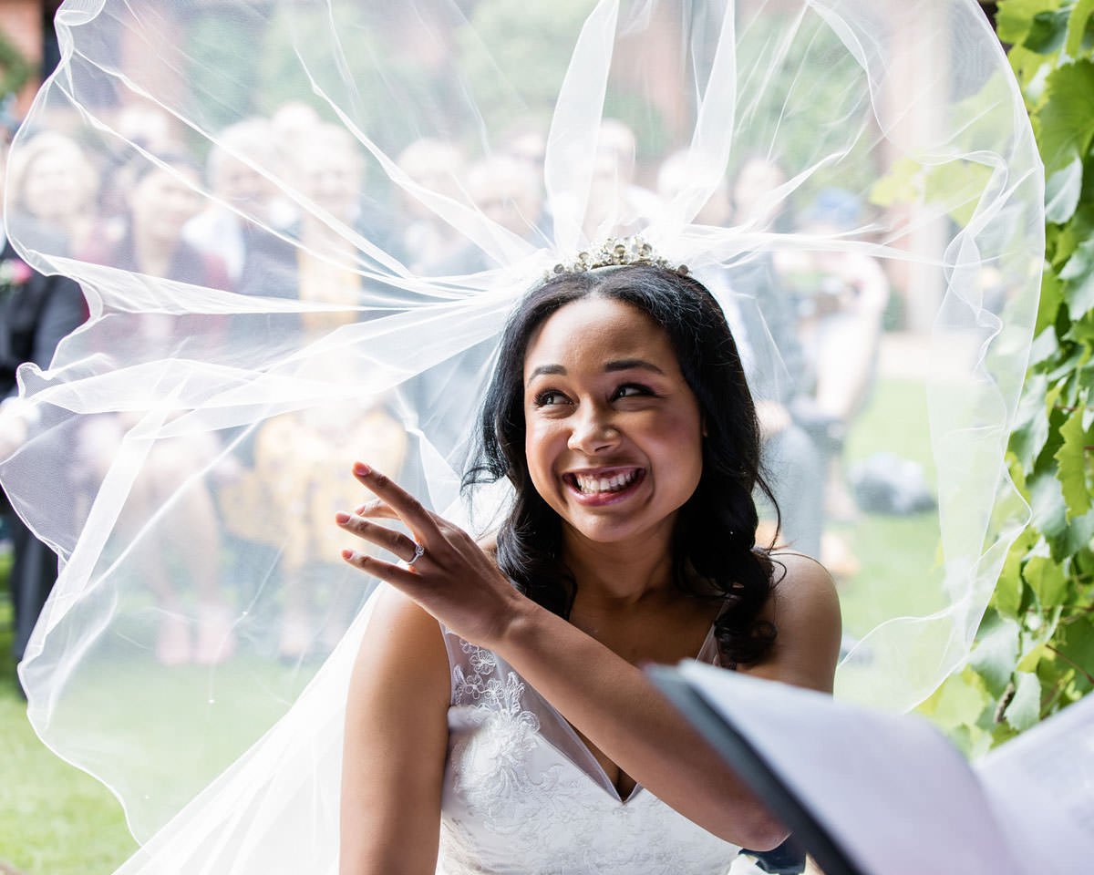 Happy smiling bride with veil blowing in the wind