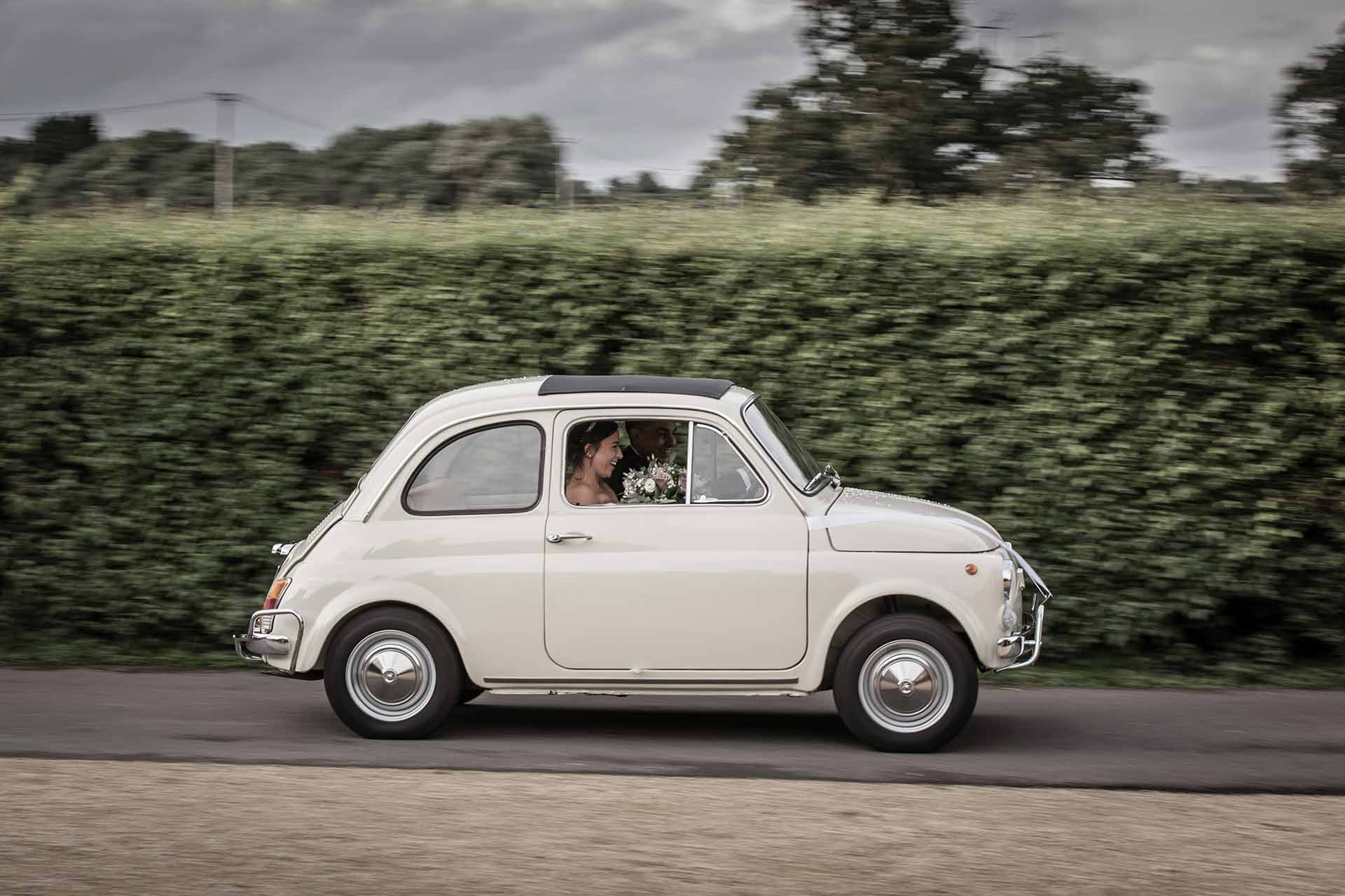 bride and groom in a Fiat 500 at a wedding