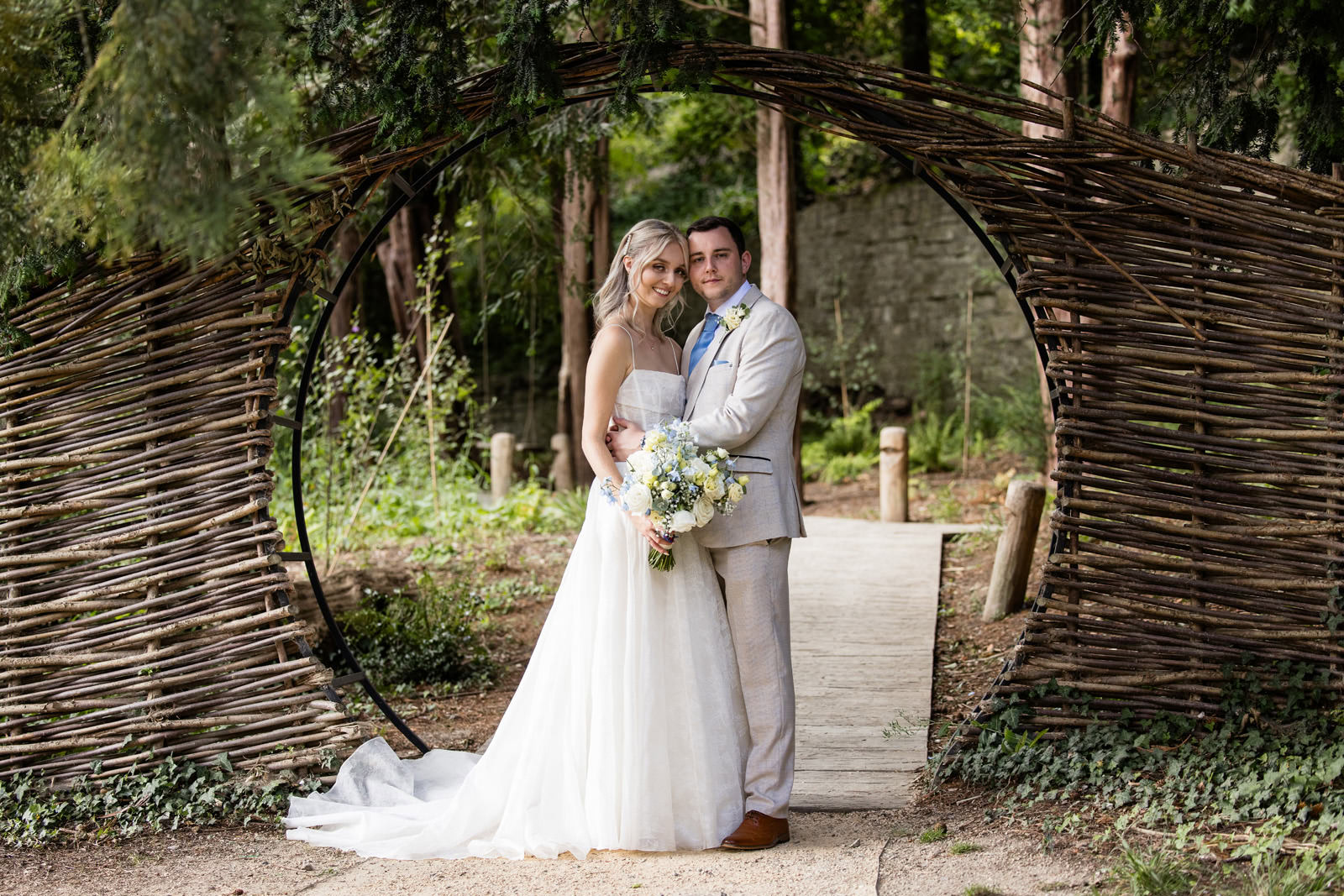 bride and groom in front of wicker arch at The Orangery in kent wedding