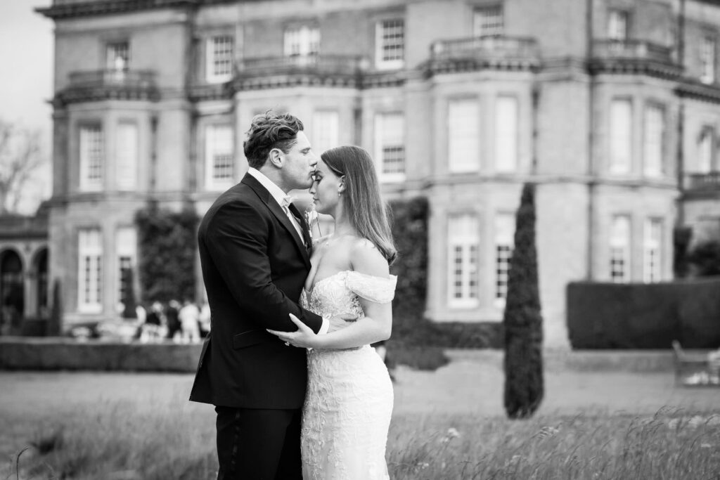 groom kisisng bride's head outside Hedsor House