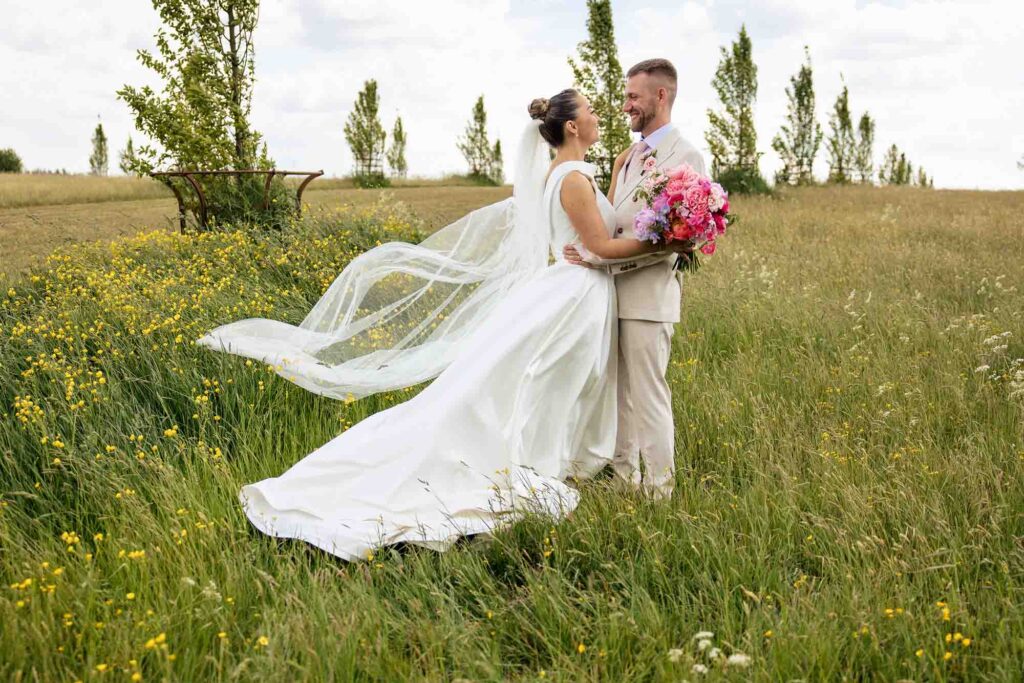 bride and groom with bride's veil blowing in wind