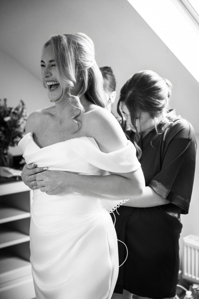 bride laughing as she has her dress tied up