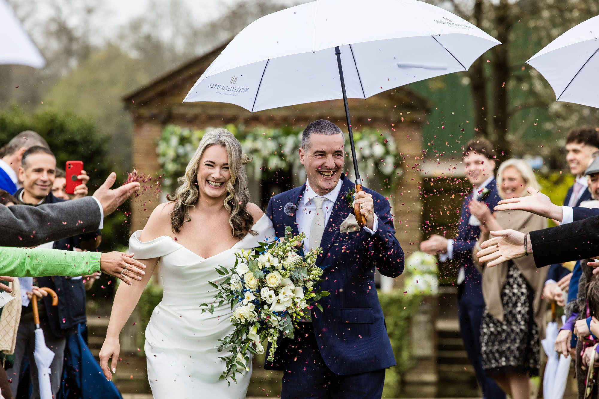 bride and groom holding umbrellas