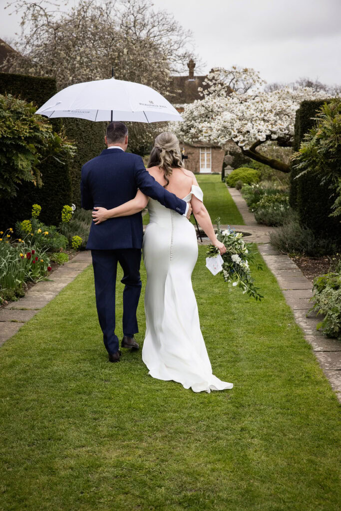 bride and groom laughing under umbrella