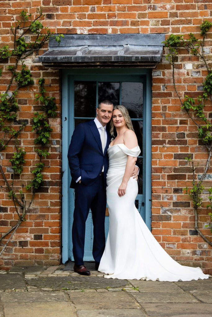 bride and groom standing in front of brick building at Micklefield Hall wedding